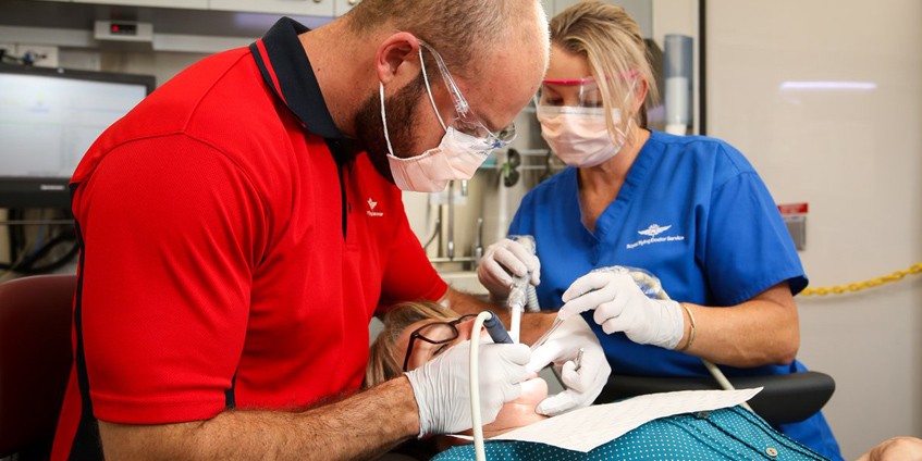 Dentist and assistant working on female patients teeth