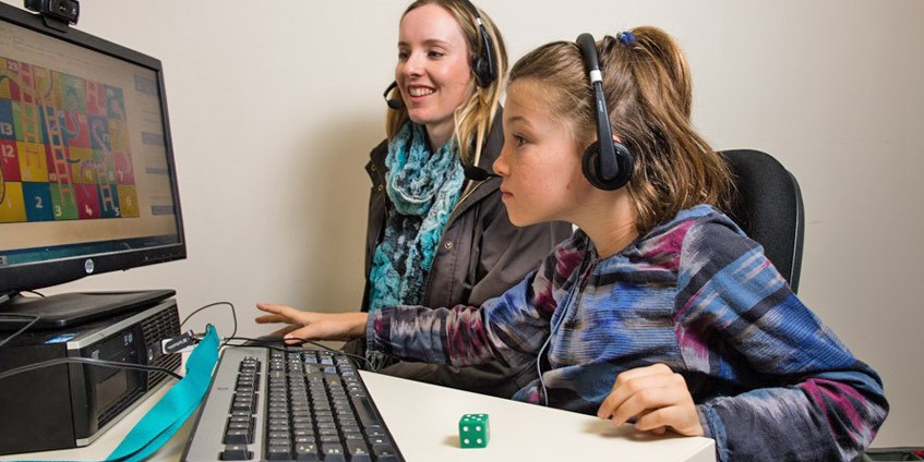 Young woman helping a young girl use a computer