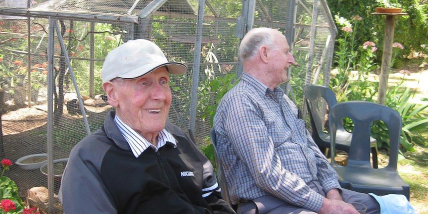 Two male seniors sitting on a garden bench