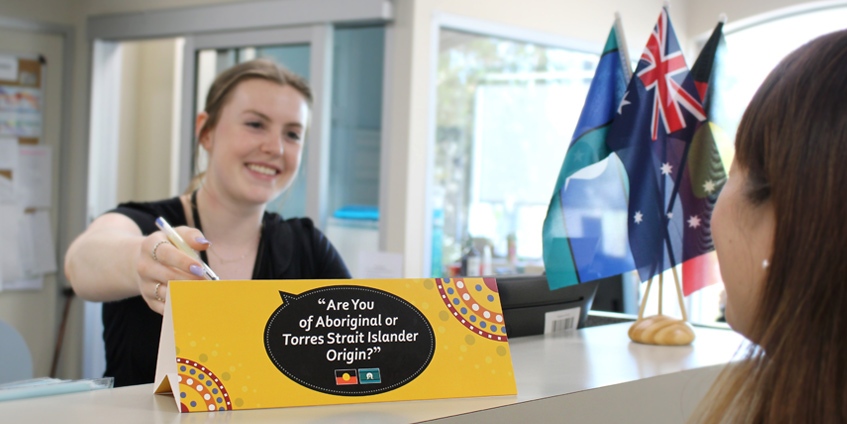 Woman pointing to sign that says are you of Aboriginal or Torres Strait Islander Origin