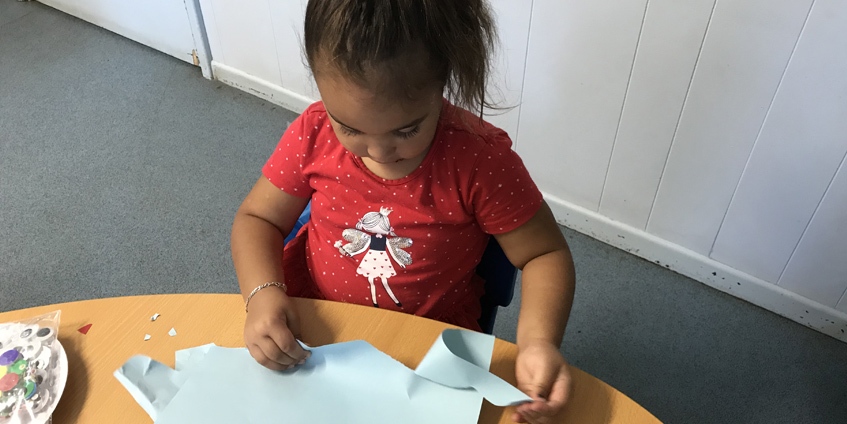 Child tearing paper at a table