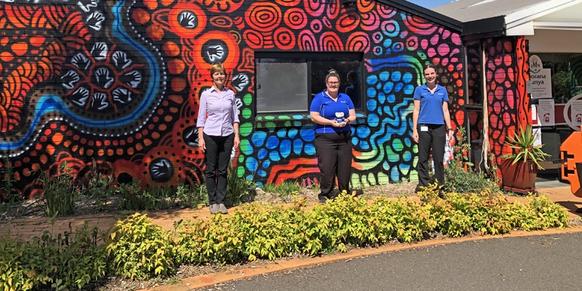 Three women in front of painted building