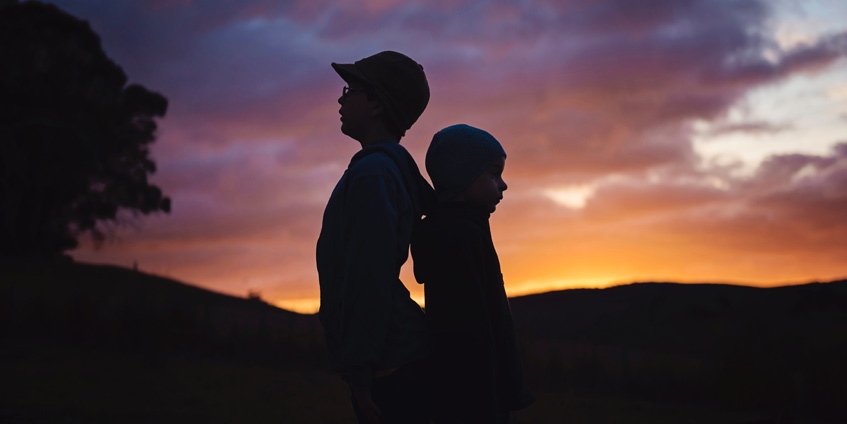 Two boys silhouetted against sunset