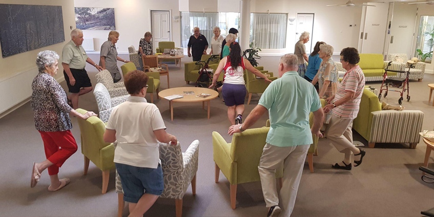 Elderly excercising around chairs