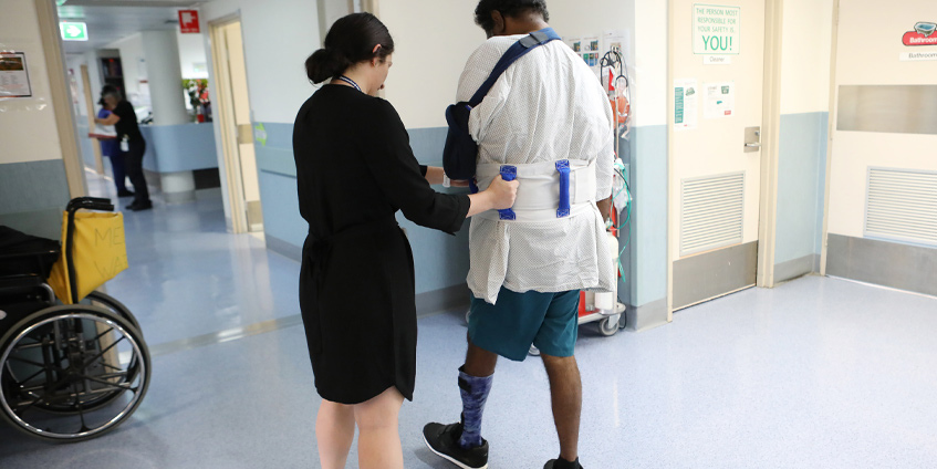 Female nurse helping a young man walk