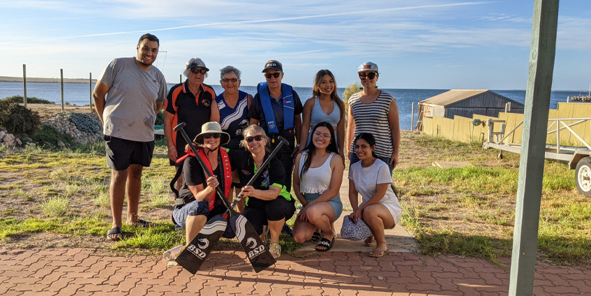 Group of people and students holding dragon boat paddles