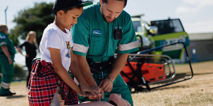 Paramedic and young boy practicing CPR