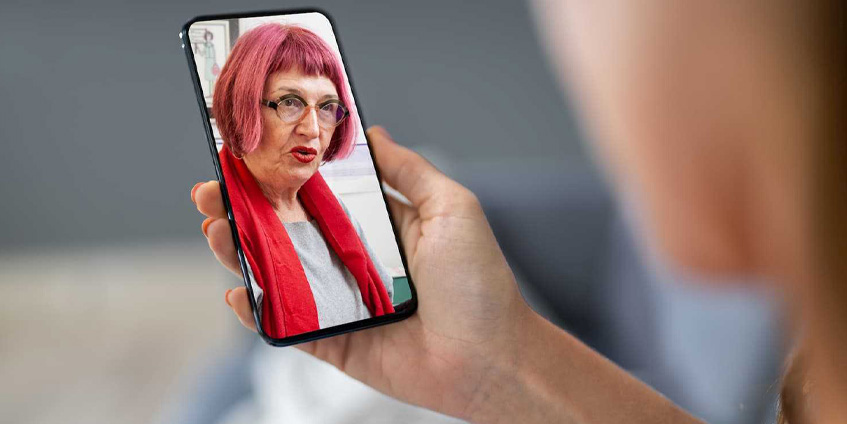 Woman holding phone video calling a woman with red hair.