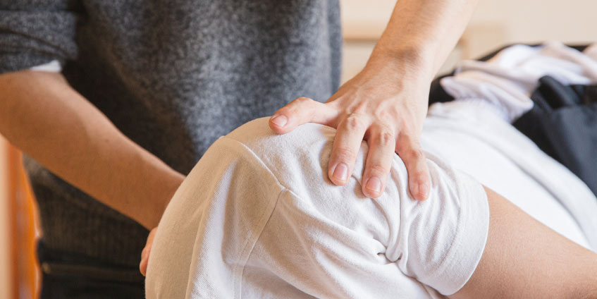 Man feeling a prone mans shoulders