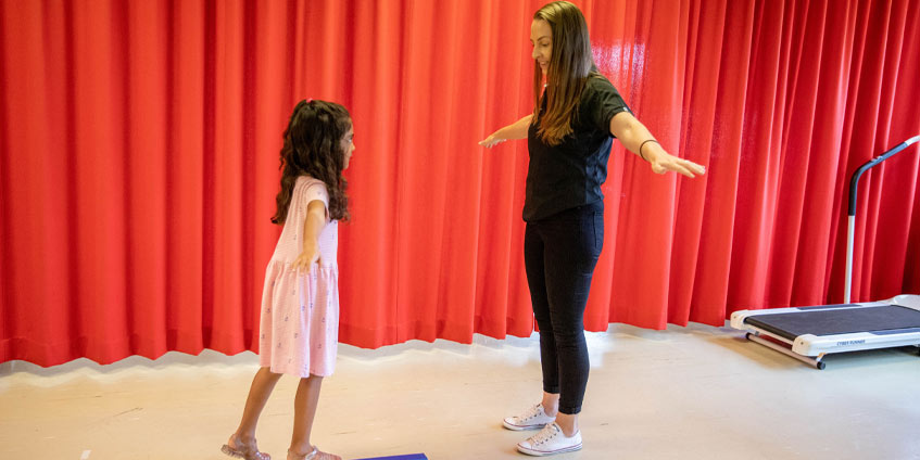 Woman with girl doing balancing exercises