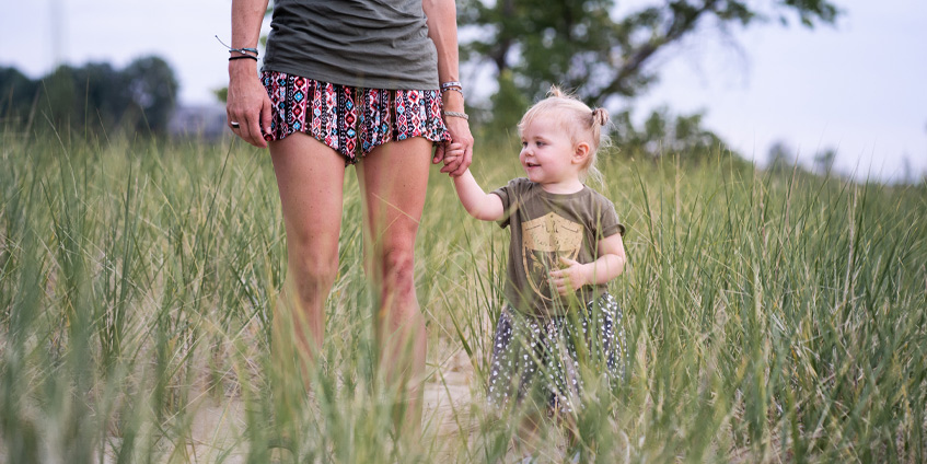 Mother with young toddler walking in the grass
