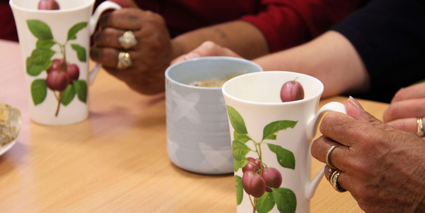 Hands and tea cups of the women’s groups that Anita runs