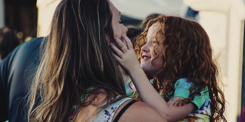 Mother holding smiling daughter