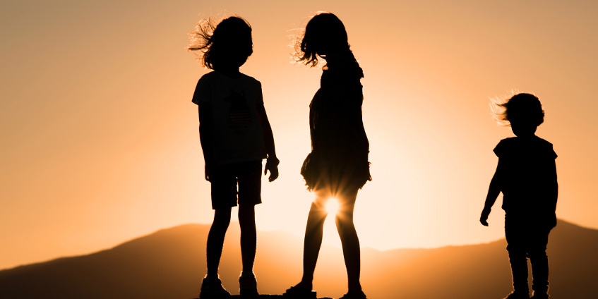 Three children silhouetted at sunset