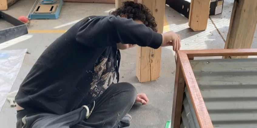 A student lacquers timber on a vegetable planter box. [Image: Thomas Sarah]