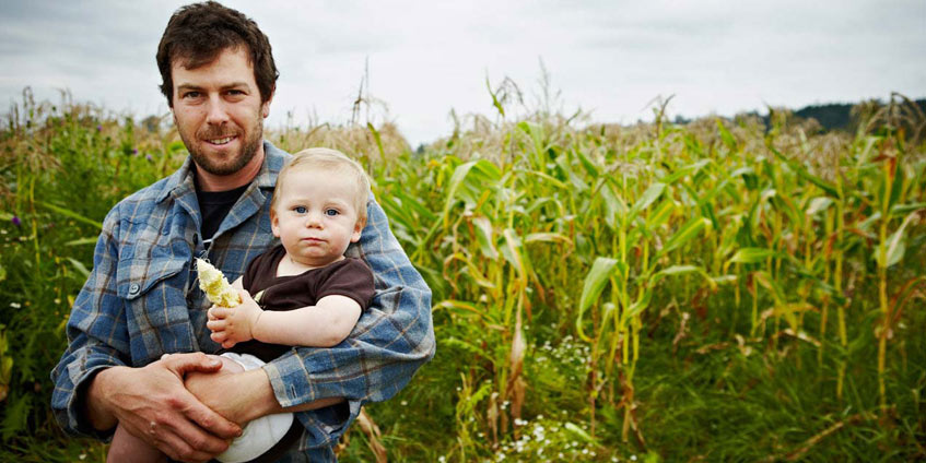 Man in corn field holding a baby