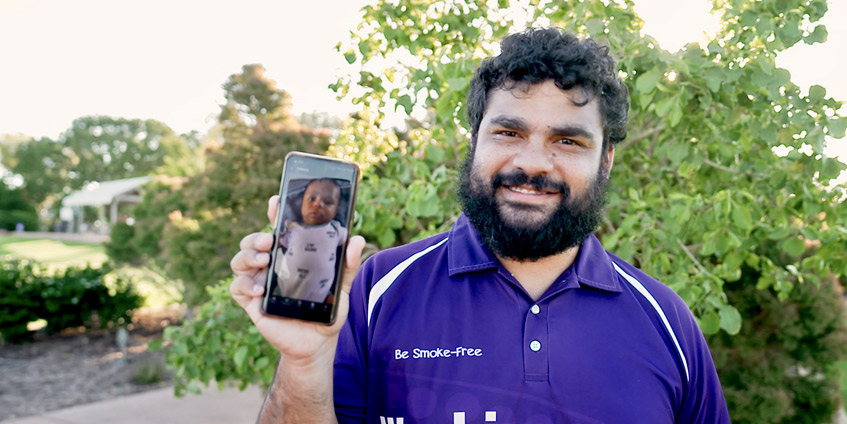 Man showing photo of his baby on mobile phone