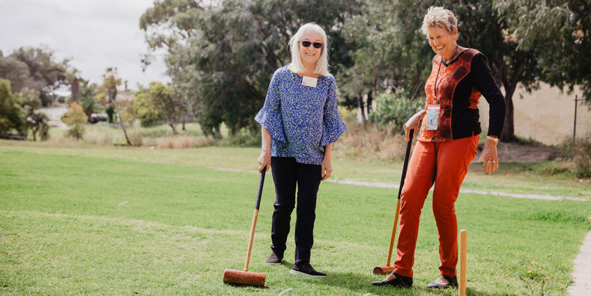 Two women playing croquet