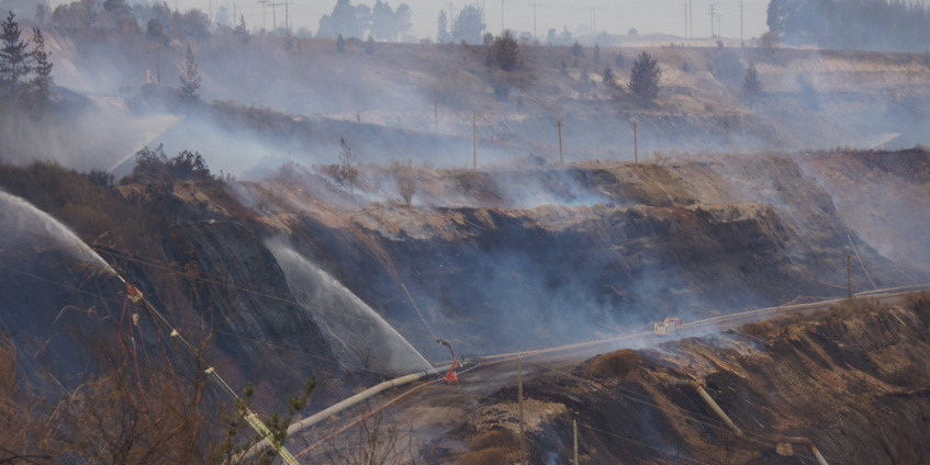 Burnt landscape with fire hoses spraying