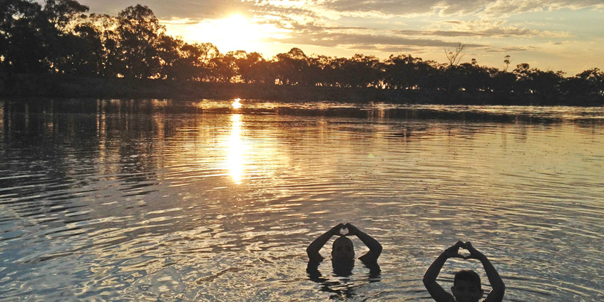 Two people swimming at sunset