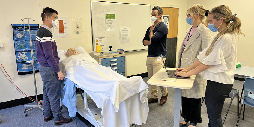 Mock ward round being recorded using GoPro video camera (black device on bedside table)’.