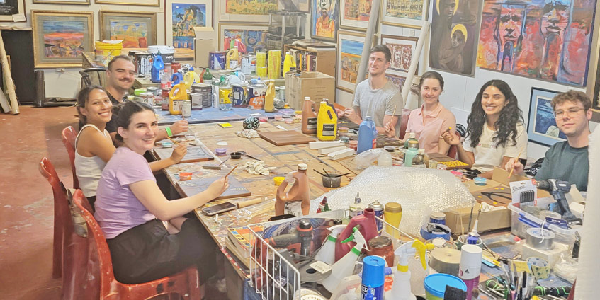 Some students seated at a table working on art projects