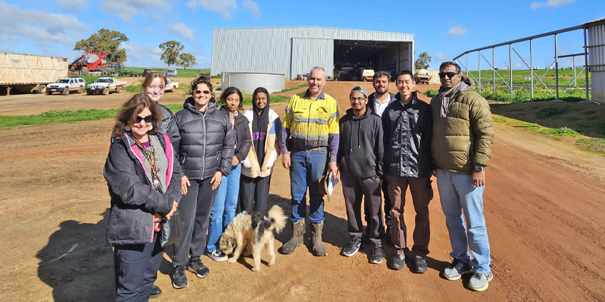 Group of students pose for photo in front of farm