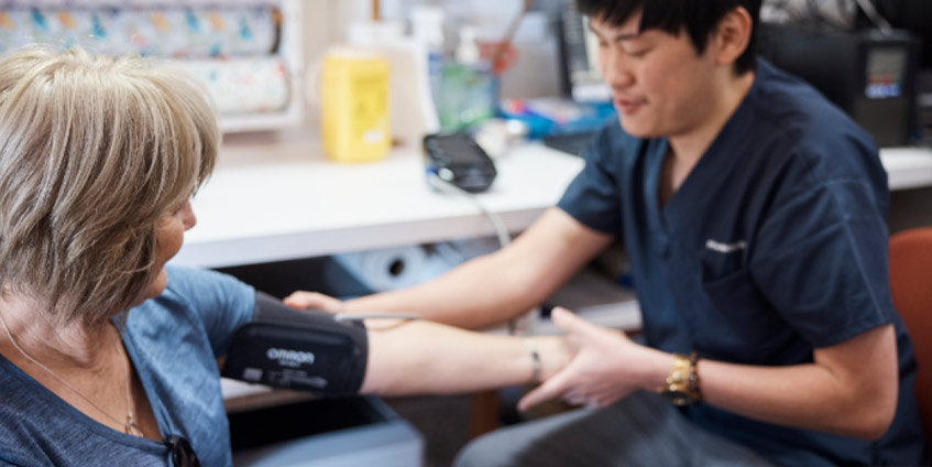 Nicholas Wong taking blood pressure measurement with female patient