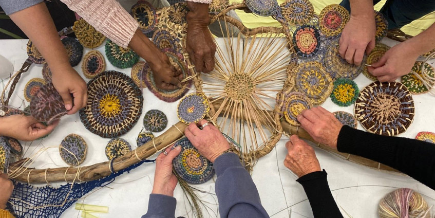 Circle of women's hands holding woven items