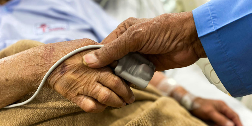 Hand holding patients hand with heart monitor on finger