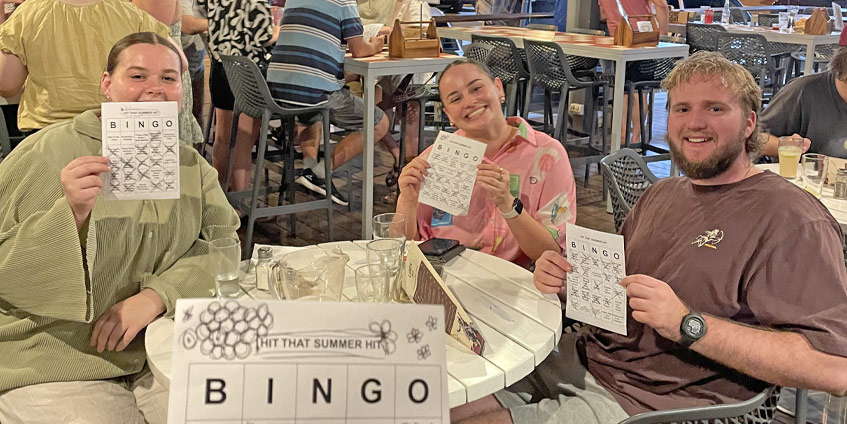 Three students playing bingo at night in a restaurant