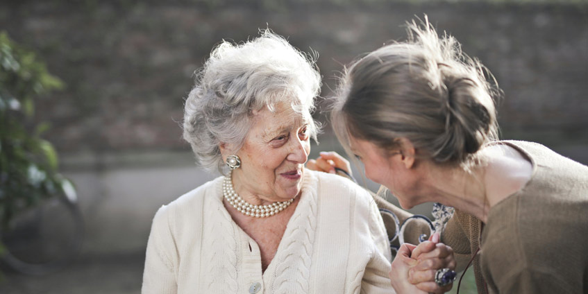 Woman talking to mature woman on park bench