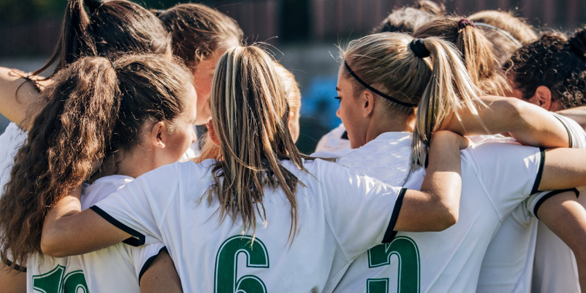 Women's sporting team hugging