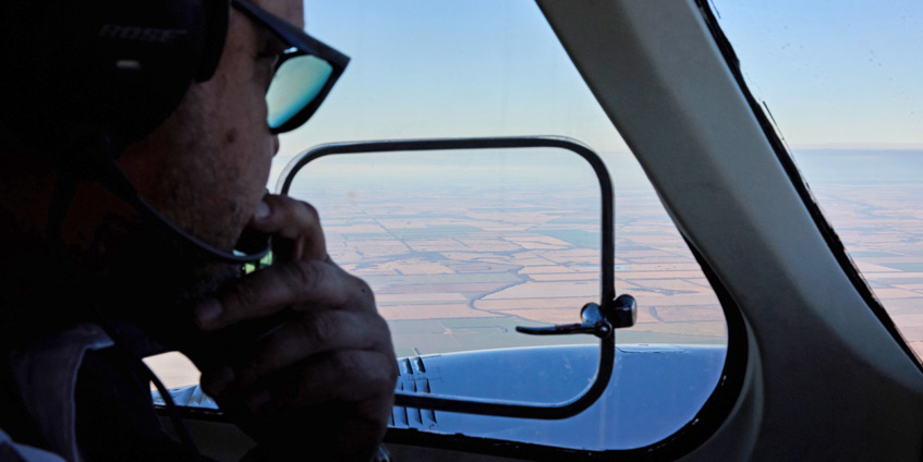 Cockpit view of Roma township with pilot in the foreground using the radio