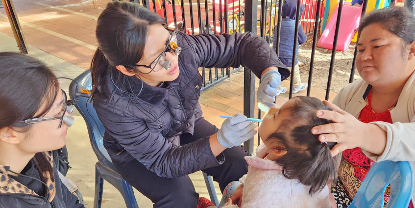 Dentist looking at a young childs mouth in a playground