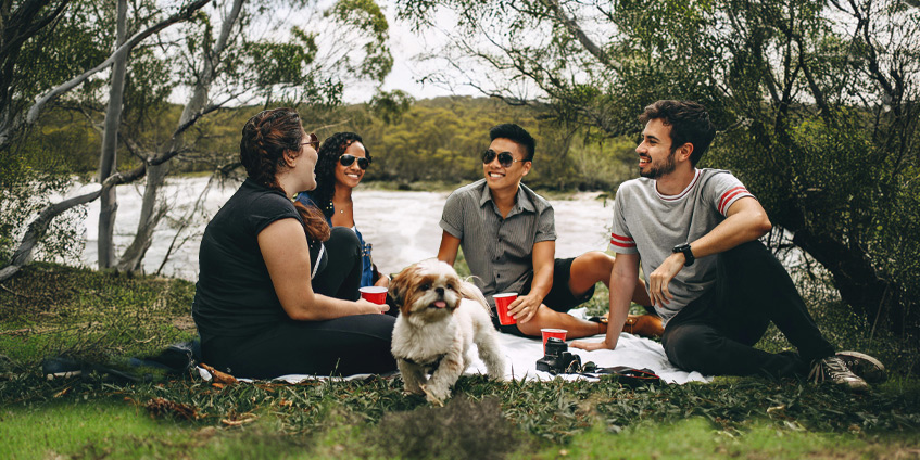 People pick-nicking besides a river in a bush setting