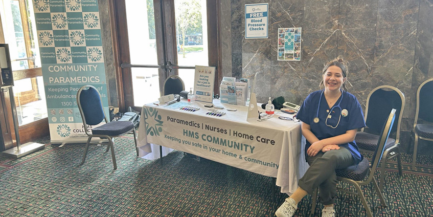 Ashlea Christenson seated indoors at a health check stand/table
