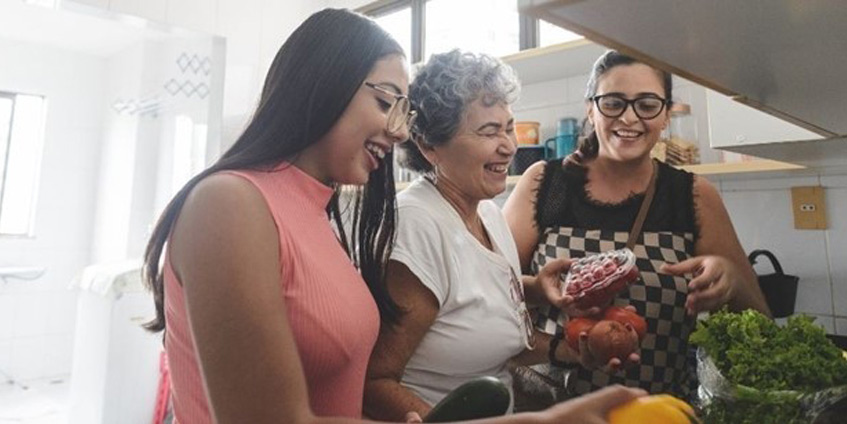 Three women in a kitchen with vegetables