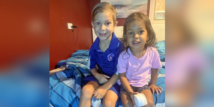 Two preschool age children sitting on a bed