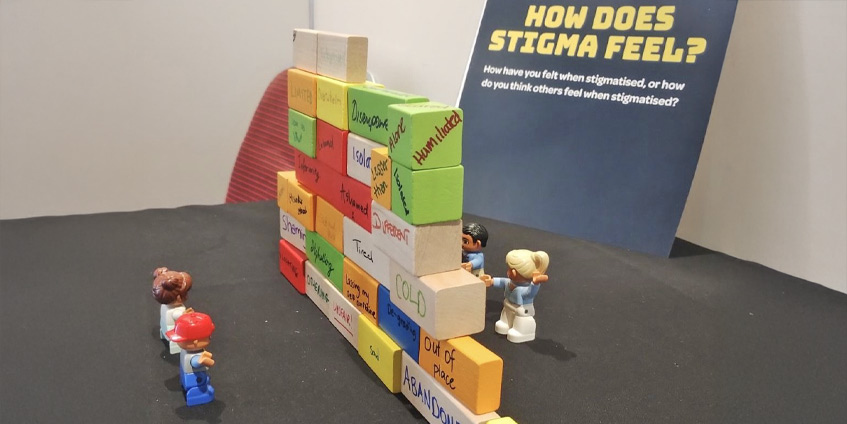 A wall of childrens blocks with emotions written on with some small toy people on either side.