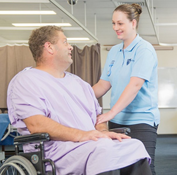 Man in wheelchair being assisted by nurse
