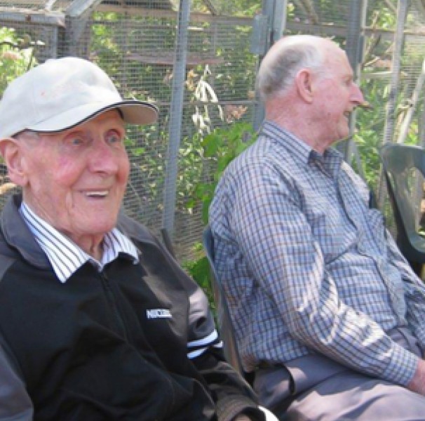 Two male seniors sitting on a garden bench
