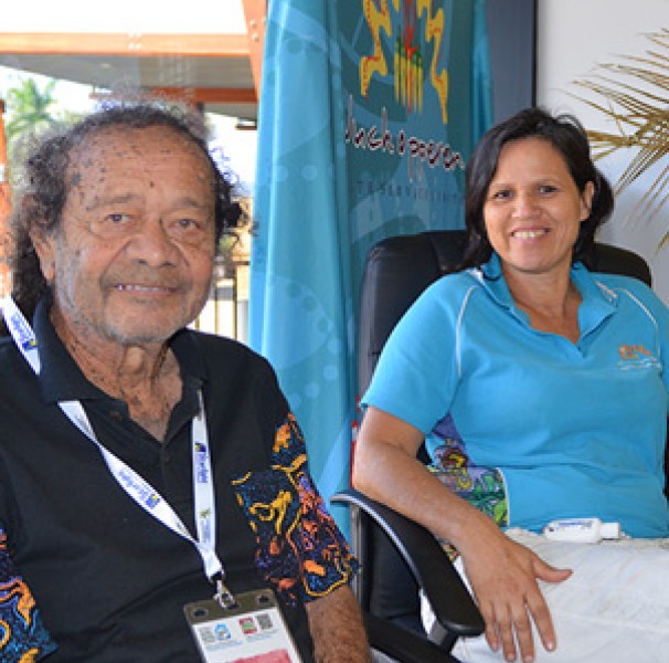 Man and woman seated Yirrkandji Elder, Georgie Skeenes with Wuchopperen staff members at the Culture, History and Healing stall at the recent conference