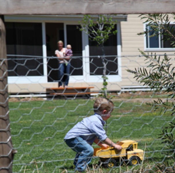 Boy playing with toy truck on front lawn