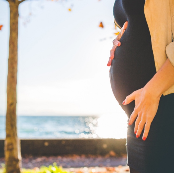 Pregnant woman in front of ocean and tree