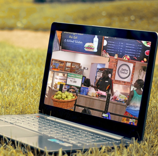 Laptop on a grassy area with a screen of a remote grocery shop