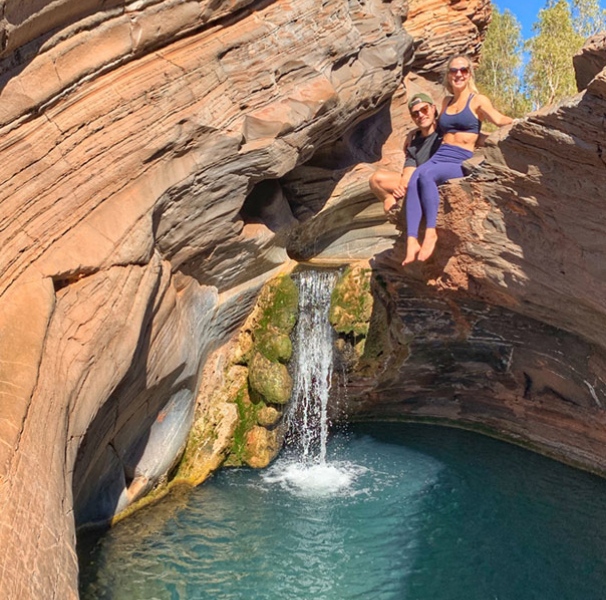 Simone and husband Dan sitting on a ledge above a rock pool.