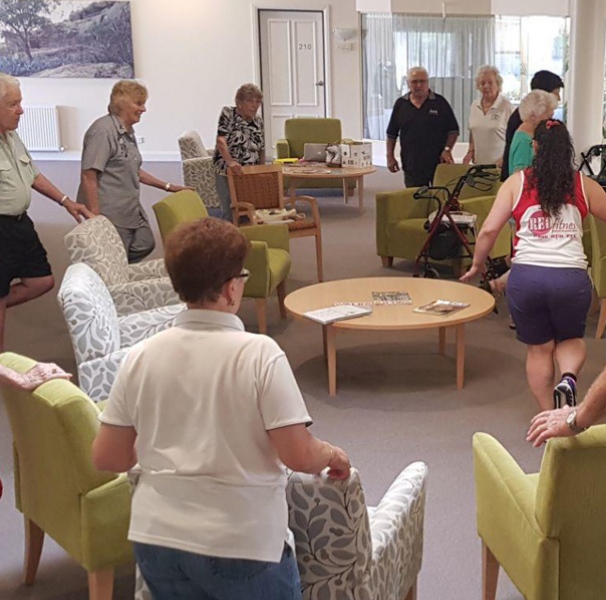 Elderly excercising around chairs