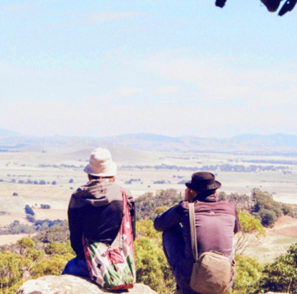 Two people sitting on rocks looking out over valley