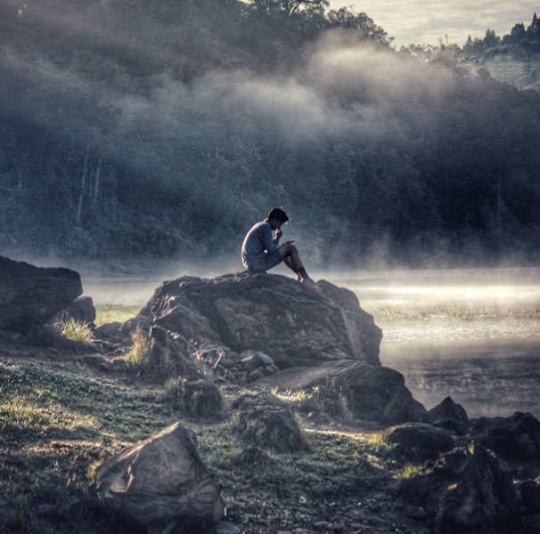 Man on rock near lake